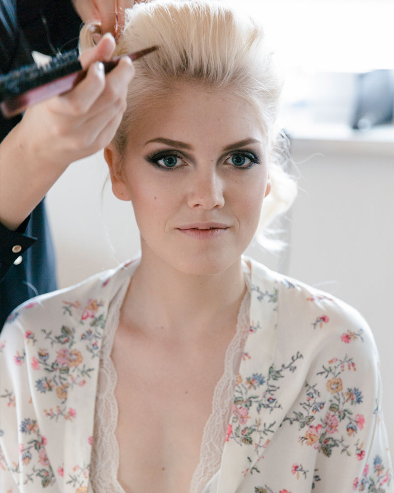 Haarstylistin steckt die Haare der Braut beim Getting Ready