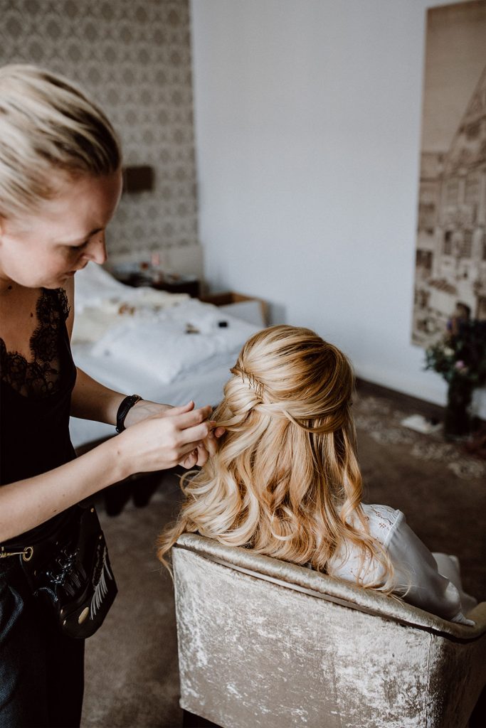 Haarstylistin kreiert eine halb gesteckte Hochzeitsfrisur