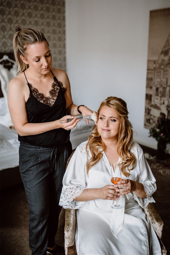 Braut genießt das Auftragen des Brautmake-ups