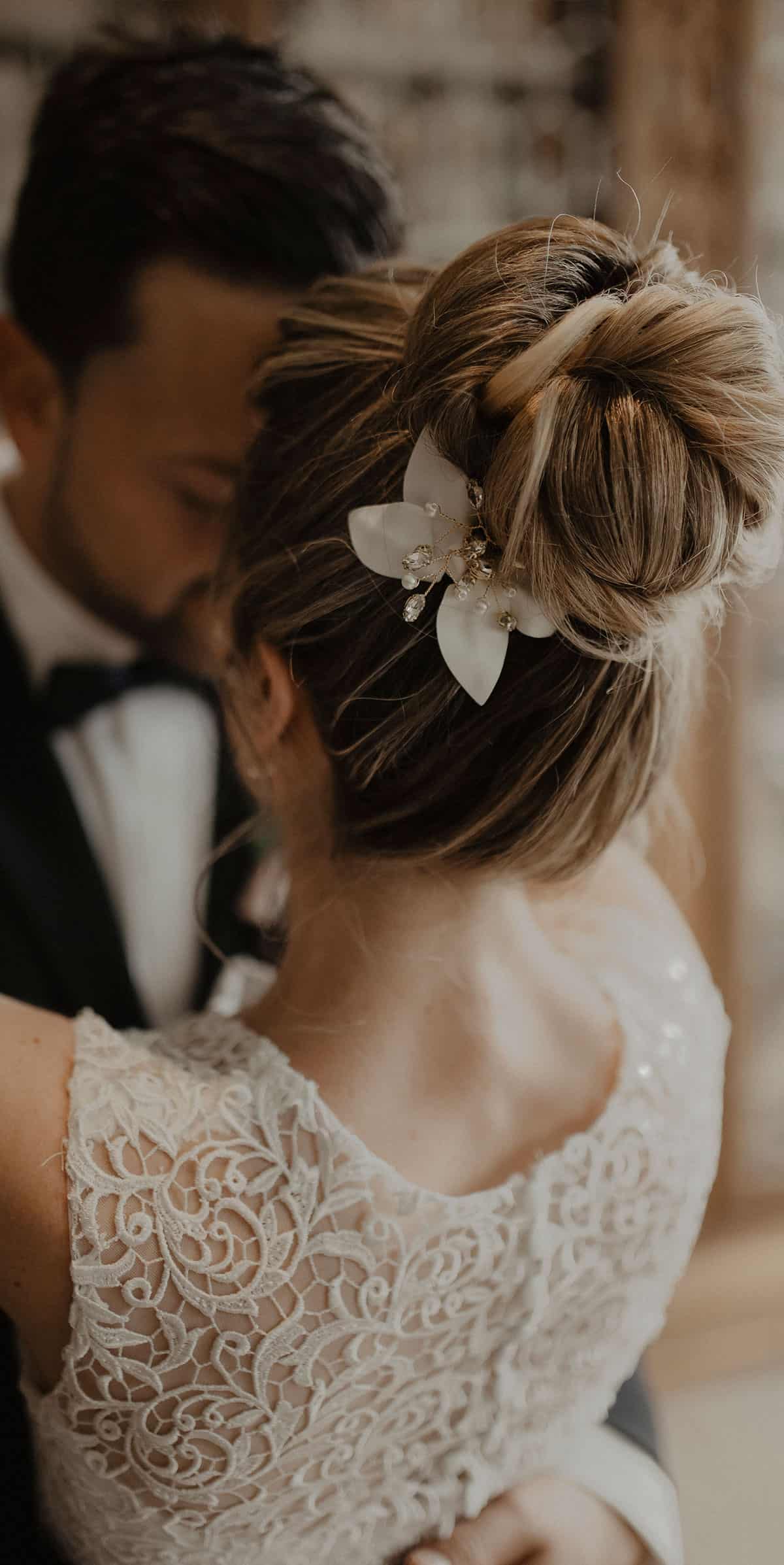 Braut trägt romantische Hochzeitsfrisur mit Haarschmuck aus Lederblüten