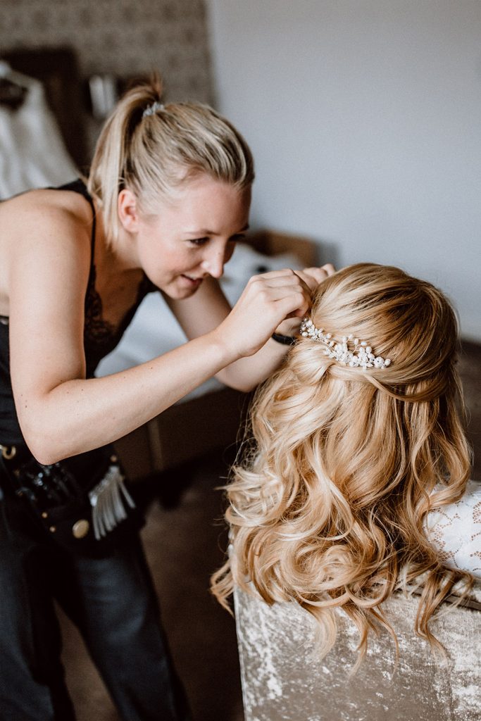 Brautstylistin hat viel Freude beim Styling der Haare