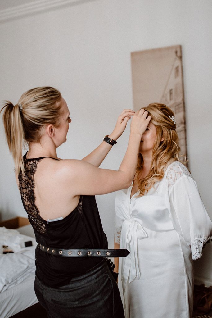 Hairstylistin legt letzte Handgriffe an der Frisur der Braut an