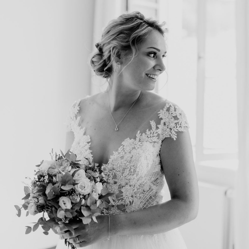 Braut in einem Vintagekleid trägt Hochzeitsfrisur mit echten Blumen