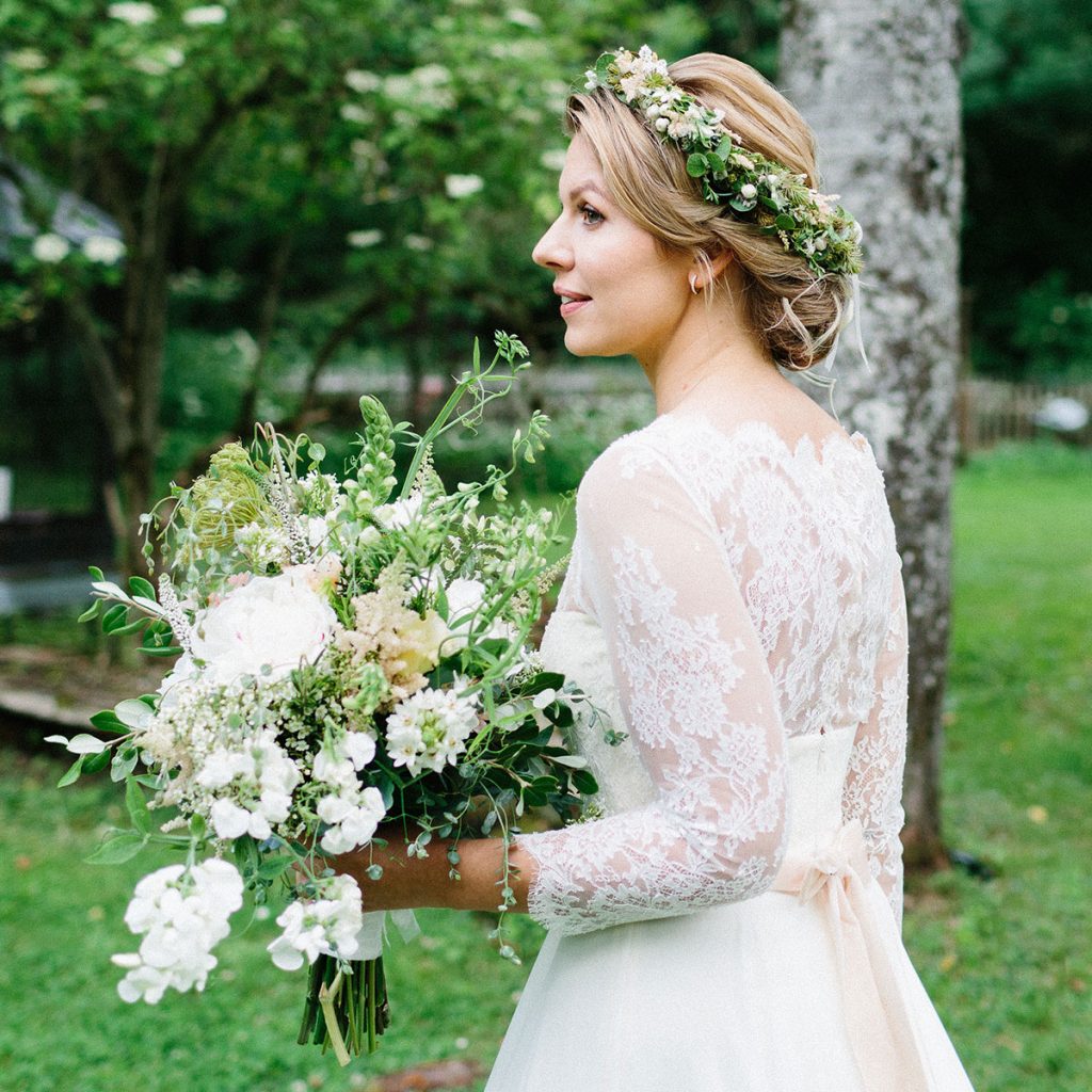 Braut im Spitzenkleid und Seidenschleife trägt Brautfrisur mit Haarkranz