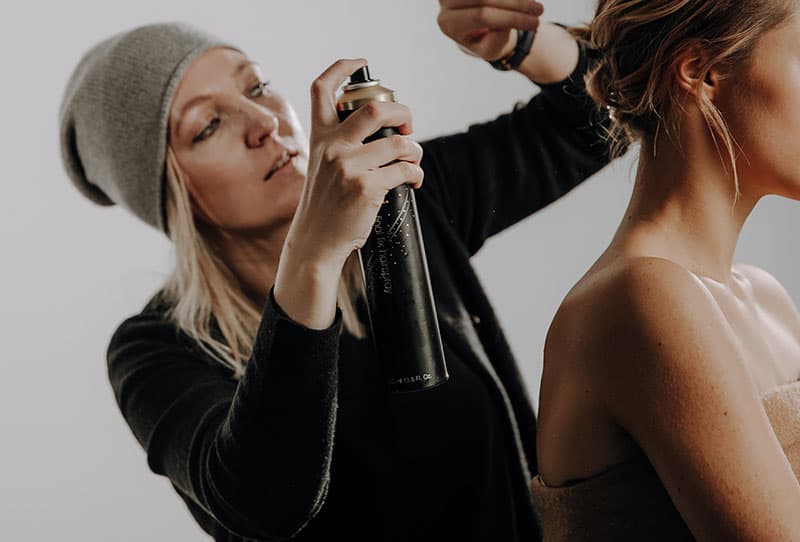 Visagistin macht Hairstyling am Fotomodel