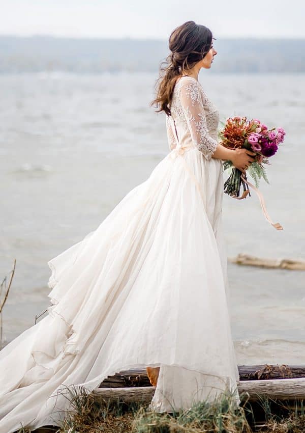 Braut steht im Wasser mit Kleid und Brautstrauss