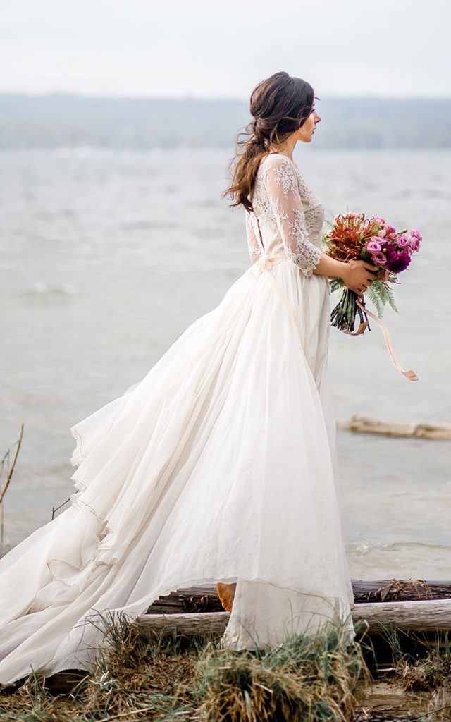 Braut steht im Wasser mit Kleid und Brautstrauss