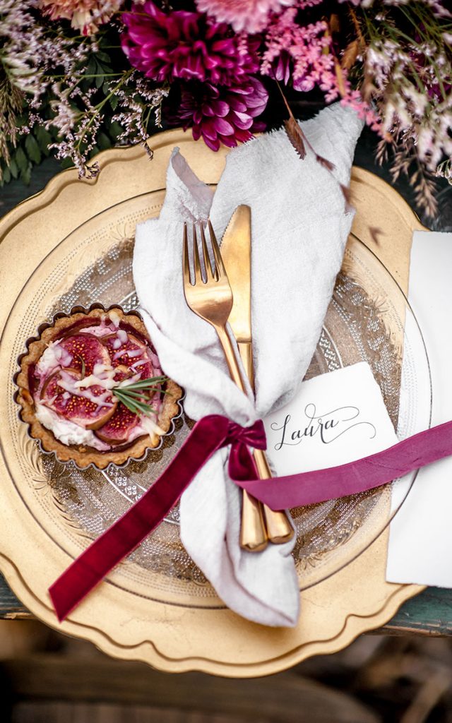 Ein goldener Teller und Besteck von oben mit Seidenband