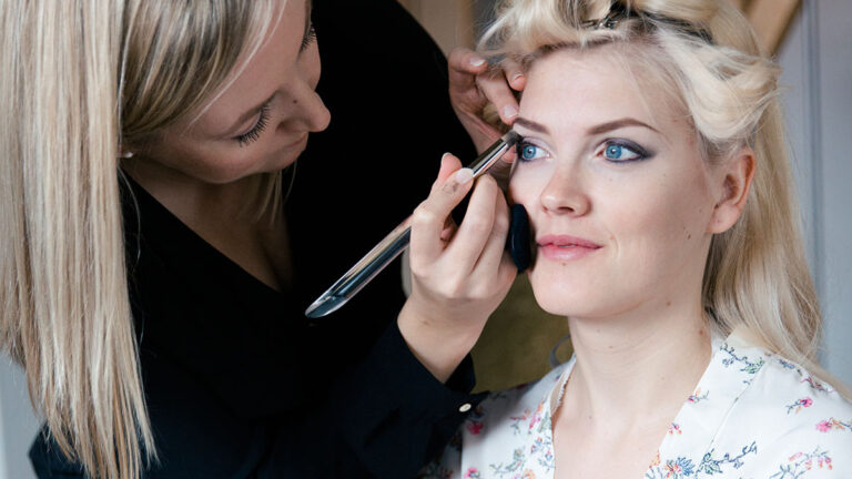 Brautstylistin trägt einer Braut professionelles Braut-Make-up auf