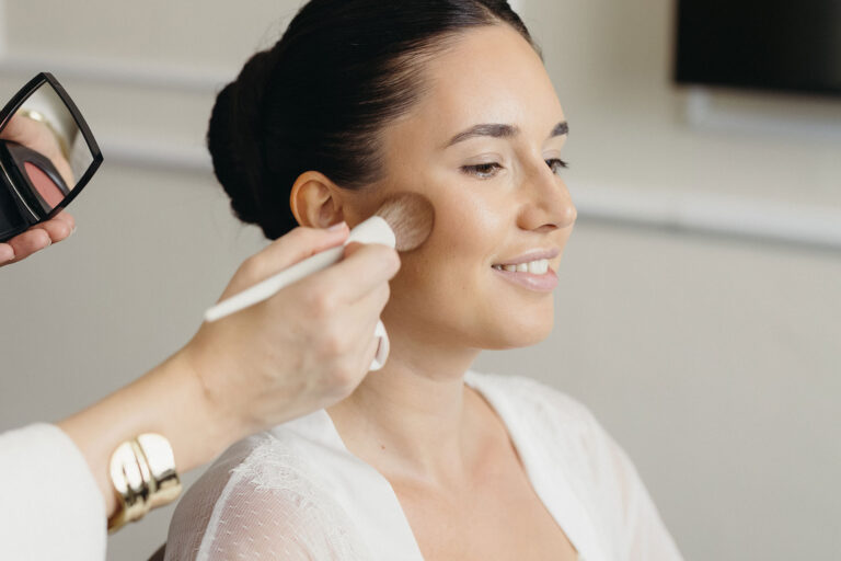 Braut beim Getting Ready während des Auftrags von natürlichem Braut Make-up mit einem Pinsel