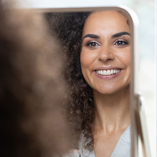 Braut Samira betrachtet ihr Braut Make-up und ihren ebenmäßigen Teint im Spiegel